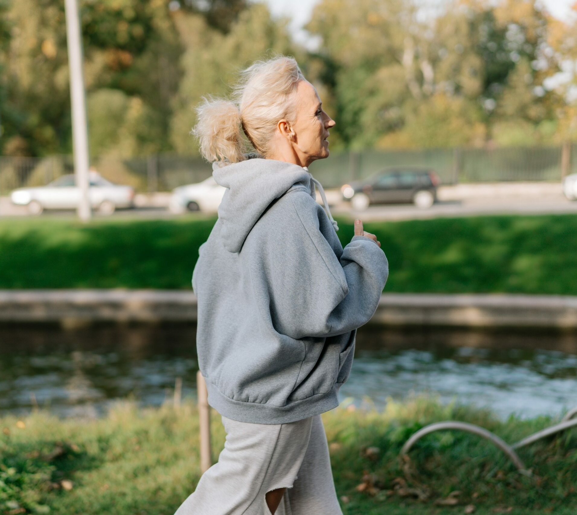 Older woman in baggy grey hoodie running outdoors